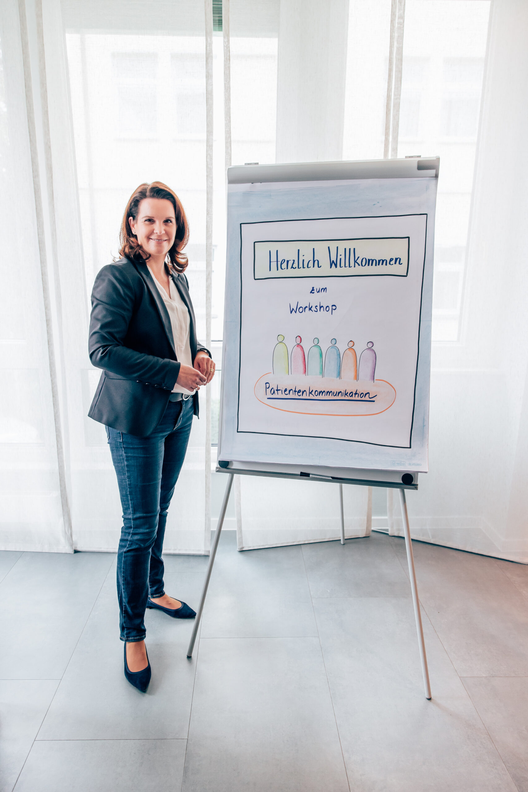 Rebekka Eitelwein steht neben einem Flipchart, das einen zu einem Workshop willkommen heißt